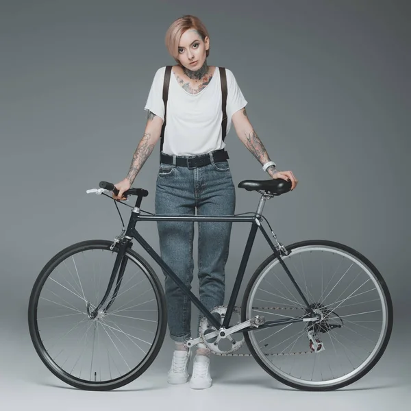 Красивая Стильная Девушка Татуировками Стоящая Велосипедом Смотрящая Камеру Изолированную Сером — стоковое фото