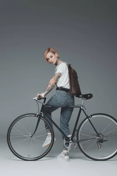 Bela Menina Tatuada Sentado Bicicleta Olhando Para Câmera Cinza — Fotografia de Stock Grátis