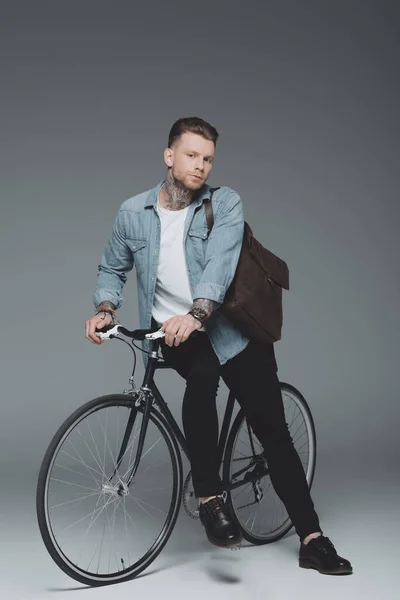 Hombre Tatuado Joven Con Estilo Sentado Bicicleta Mirando Cámara Gris — Foto de Stock