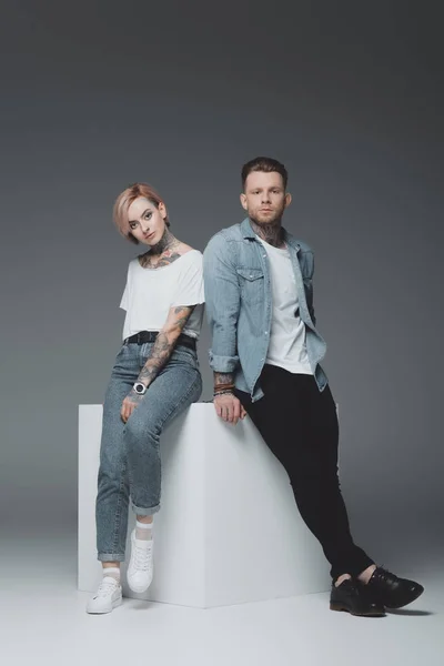 Stylish Young Tattooed Couple Sitting Together Looking Camera Isolated Grey — Stock Photo, Image