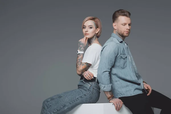 Stylish Young Tattooed Couple Sitting Back Back Looking Camera Isolated — Stock Photo, Image