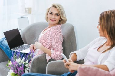 Smartphone ve dizüstü bilgisayar ile boş ekran kullanarak çekici gülümseyen kız