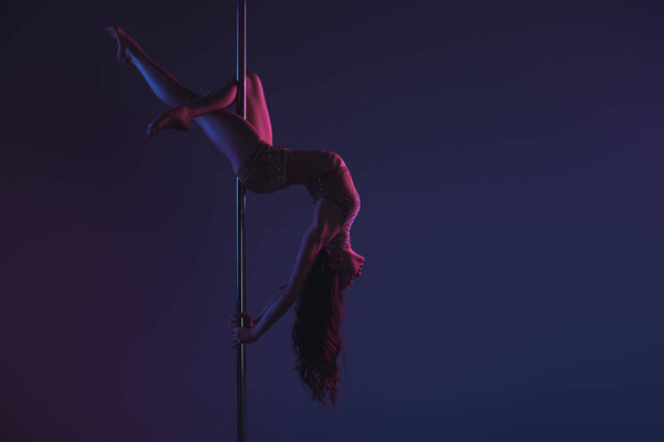 beautiful sensual flexible girl exercising with pole on blue 