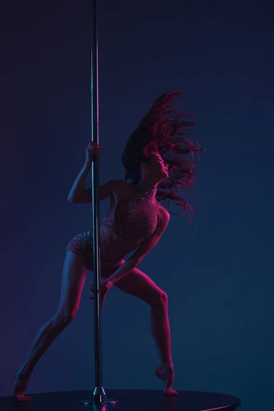 seductive athletic woman dancing with pole on blue