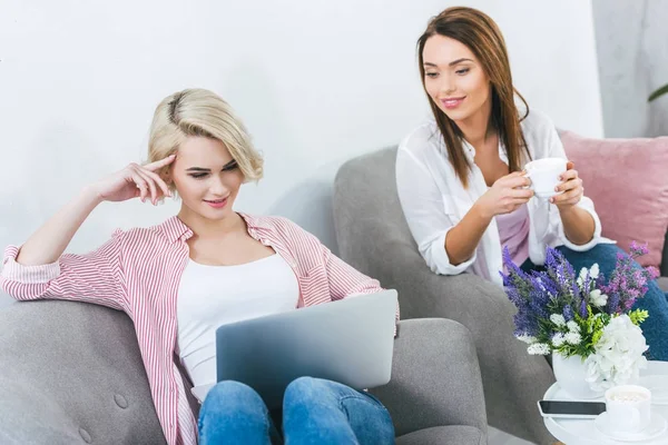 Chica Feliz Usando Ordenador Portátil Mientras Que Amigo Sosteniendo Taza — Foto de Stock