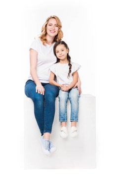 Anne kızı birlikte beyaz izole beyaz küp üzerinde otururken sarılma