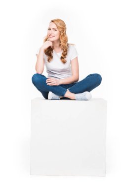 gülümseyen boş beyaz küp üzerinde beyaz izole oturan kadın