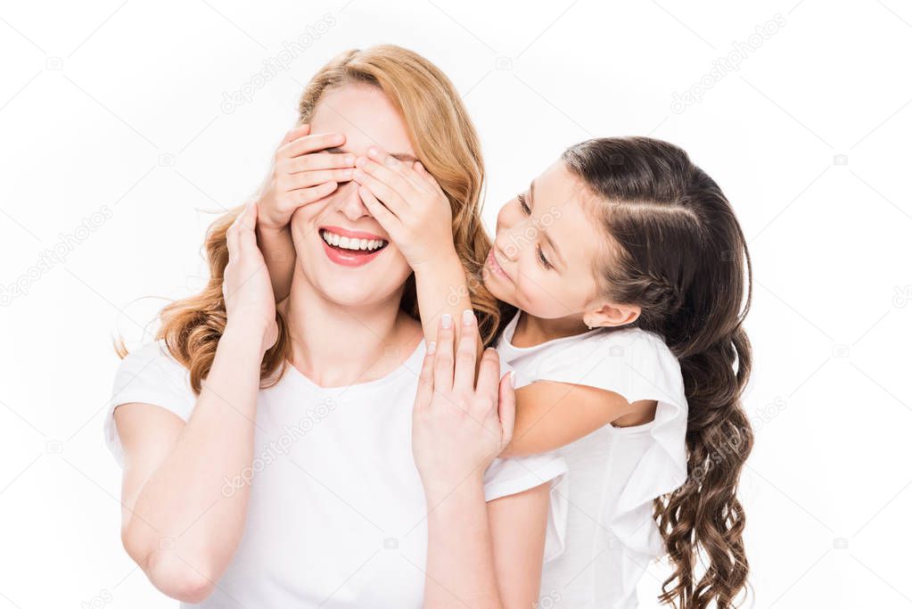 portrait of child covering eyes to smiling mother isolated on white