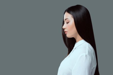 profile portrait of beautiful young asian woman standing isolated on grey