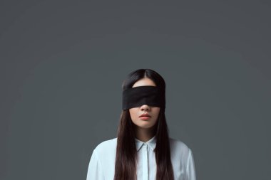 brunette girl wearing black blindfold isolated on grey clipart