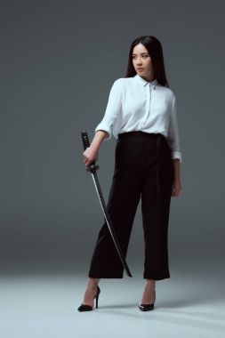 katana tutarak ve uzak gri arıyorum güzel genç Asyalı kadın görünümünü tam uzunlukta 