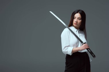 Katana kılıcı tutan ve Dış saha üzerinde izole gri seyir çekici genç Asyalı kadın  