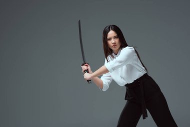 Katana kılıcı ile mücadele ve gri izole kamera bakarak genç Asyalı kadın 