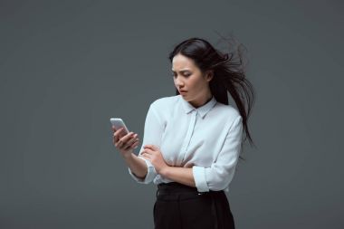 gri izole smartphone kullanarak ciddi genç Asyalı kadın
