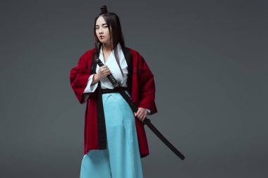 katana kılıcı tutan ve gri izole kamera bakıyorsun kimono içinde genç Asyalı kadın 