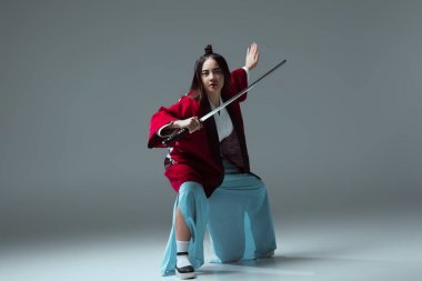 katana kılıcı ile mücadele ve gri kameraya bakarak kimono içinde Asyalı kadın