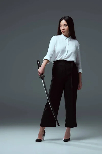 刀を押しながらグレーのよそ見の美しい若いアジア女性の完全な長さのビュー — ストック写真