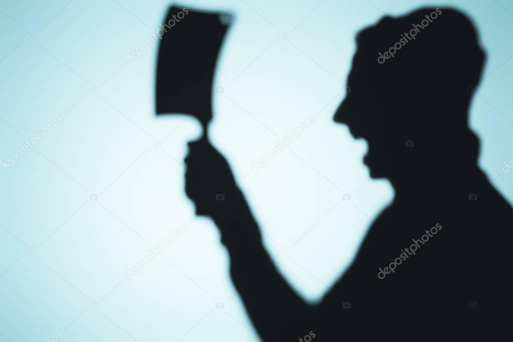 scary shadow of screaming person holding meat knife on blue