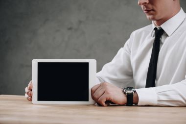 partial view of businessman holding digital tablet with black screen clipart