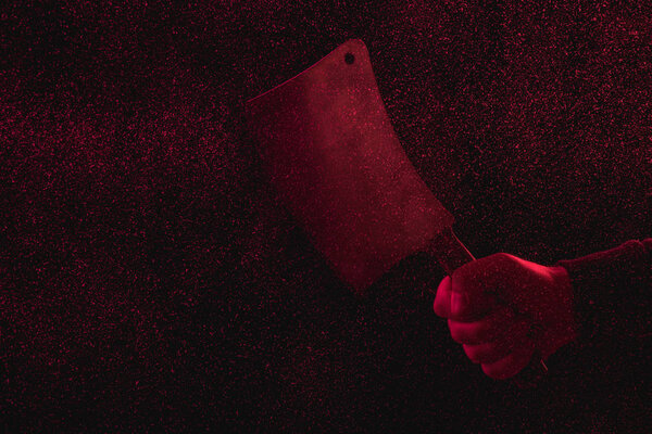 cropped shot of man holding meat knife in red light