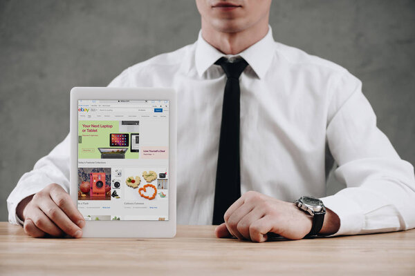 cropped shot of businessman holding digital tablet with ebay website on screen 