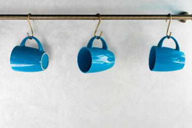 close-up view of empty blue cups hanging in kitchen clipart
