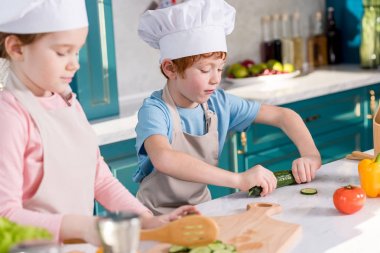 Çocuk chef şapka ve önlük birlikte mutfakta sebze salatası hazırlama