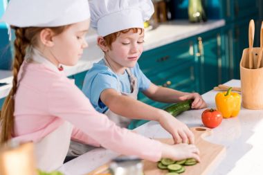 şirin çocuklar chef şapka ve önlük birlikte mutfakta sebze salatası hazırlama