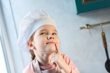 çok güzel çocuk gülümseyen ve uzak mutfakta seyir Şef şapkalı