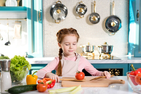 adorable little child in apron cooking in kitchen
