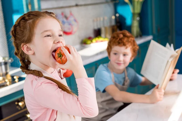Ładny Chłopczyk Książki Kucharskiej Ogląda Dziecko Jedzenie Pomidor Pierwszym Planie — Zdjęcie stockowe