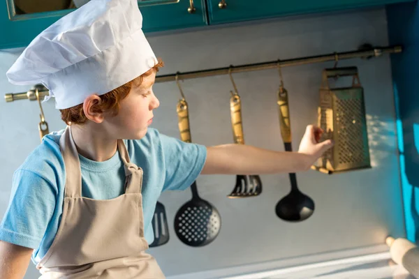 Adorable Niño Sombrero Chef Delantal Mirando Los Utensilios Mientras Está — Foto de stock gratis