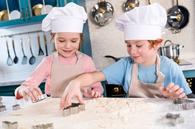 çok güzel küçük çocuklar chef şapka ve önlük kurabiye birlikte hazırlanıyor  
