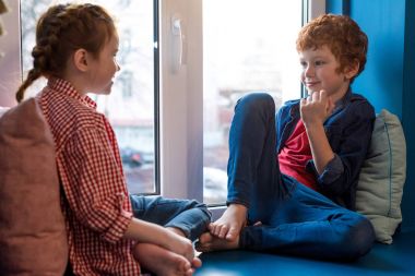 sevimli küçük her diğer kenarında otururken gülümseyen çocuklar 