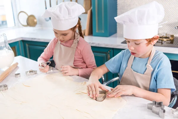 可爱的小孩子在厨师帽子和围裙一起准备饼干 — 图库照片