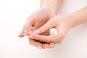 částečný pohled dívky s přírodní manikúru držení daisy, izolované na bílém