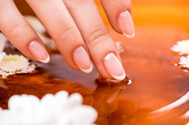 cropped view of woman making bath with flowers for nails clipart