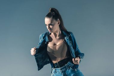 gri izole trendy denim giysiler içinde poz seksi genç kadın