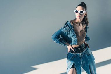 fashionable brunette model posing in denim style and sunglasses clipart