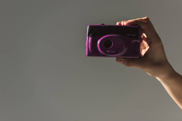 cropped view of female hand holding purple photo camera, isolated on grey