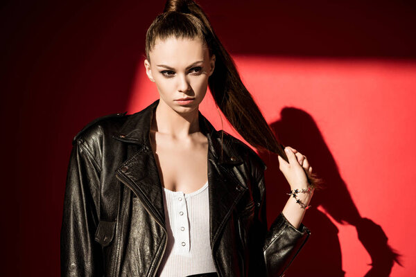 stylish girl with ponytail hairstyle posing in black leather jacket for fashion shoot  
