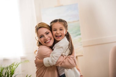 mutlu anne ve sarılma ve evde kameraya gülümseyen kız