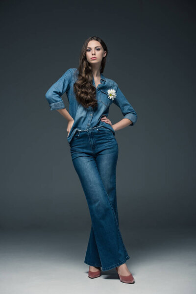 beautiful girl with long hair posing in flare jeans, on grey