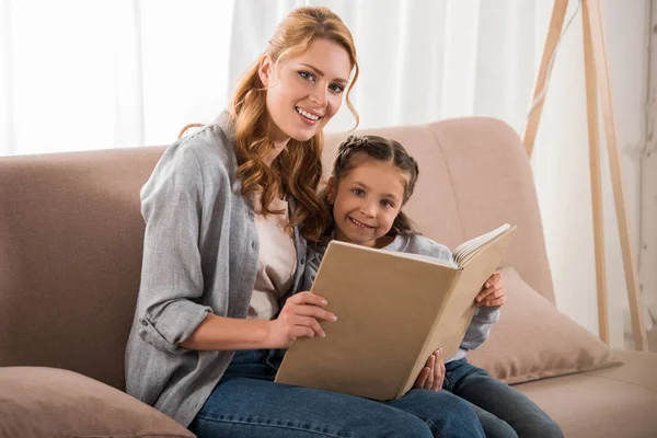 Feliz Madre Hija Leyendo Libro Sonriendo Cámara Juntos Casa — Foto de Stock