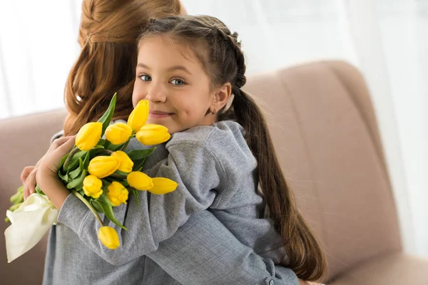 Bambino Con Tulipani Gialli Che Abbracciano Madre Sorridono Alla Macchina — Foto Stock