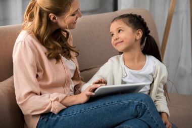 mutlu anne ve her diğer dijital tablet evde kullanırken gülümseyen kız