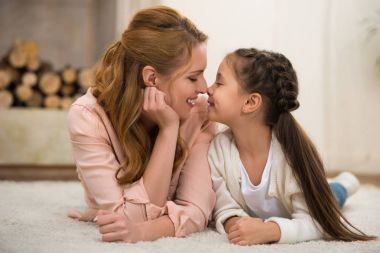 güzel mutlu anne ve kızı yan yana halı üzerinde yatarken