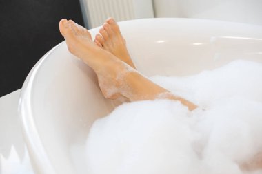 cropped shot of female legs in bath with foam