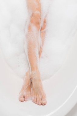 partial view of female legs in bath with foam clipart