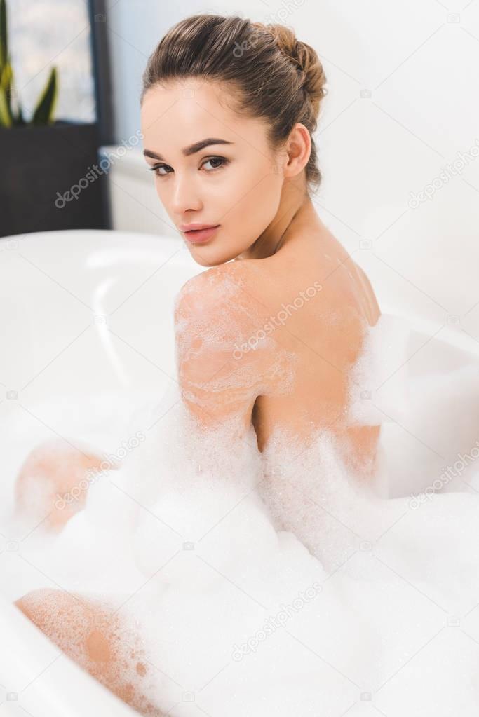 side view of beautiful young woman taking bath at home